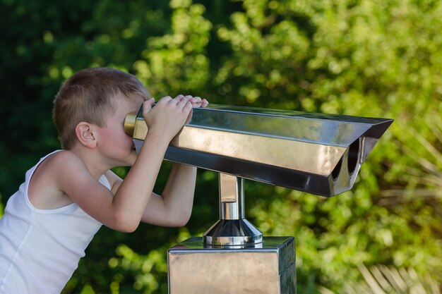 Niño mira a través del telescopio en vistas de la ciudad.