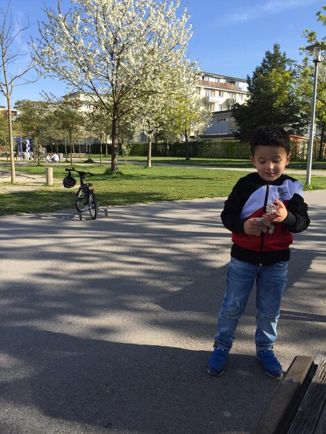 Foto niño mirando hacia abajo mientras está de pie en el parque