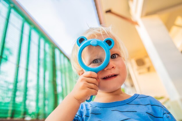 Niño mirando con una lupa contra el fondo del jardín Educación en el hogar