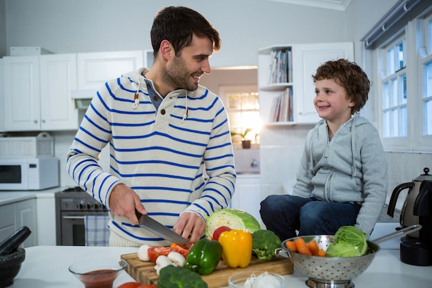 Niño mirando mientras padre cortando verduras