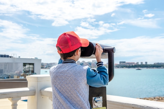 Niño mirando por el ocular del telescopio turístico Viajes destino turístico ampliación del paisaje