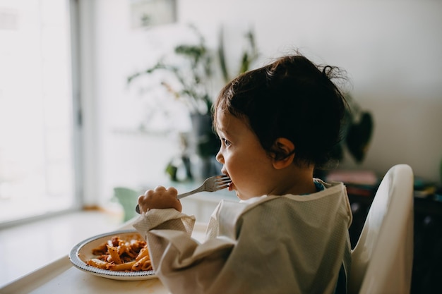 Niño mirando hacia otro lado mientras está sentado en la mesa