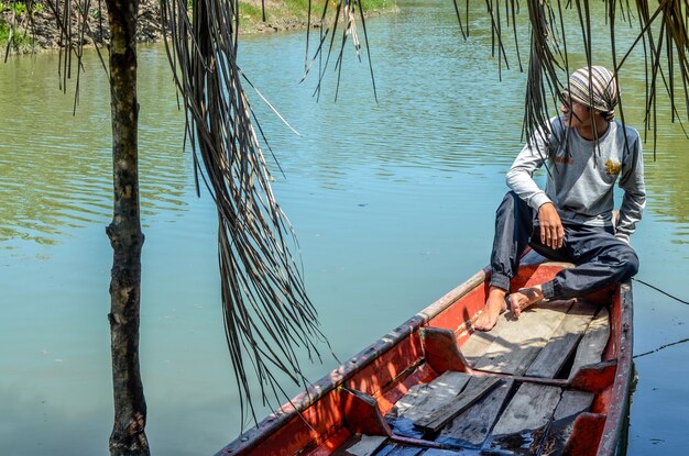 Foto niño mirando hacia otro lado mientras está sentado en un barco en el lago