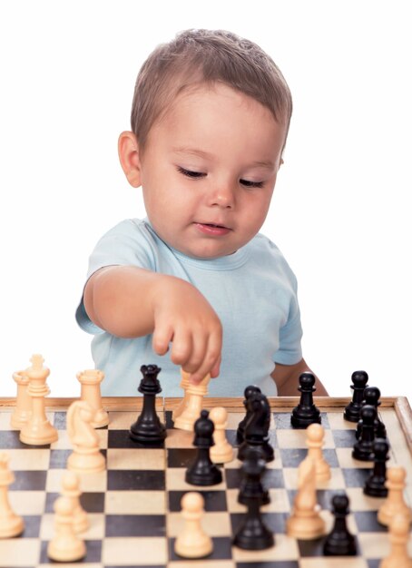 Niño mirando las piezas de ajedrez aisladas sobre fondo blanco.