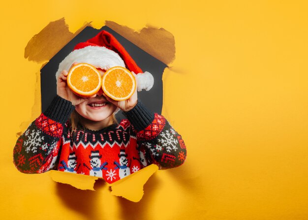 Niño mirando el regalo de Navidad a través de naranja sobre fondo negro