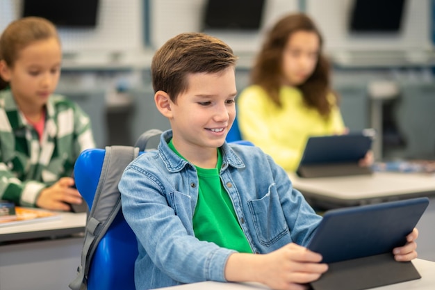 Niño mirando tableta en la lección de la escuela