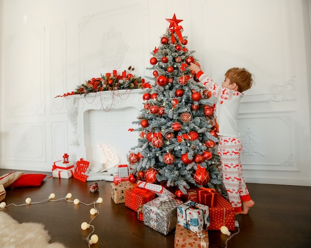 El niño mismo decora el árbol de Navidad.