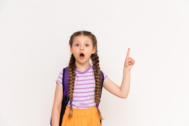 Un niño con una mochila escolar señala su anuncio sobre un fondo blanco aislado Una niña pequeña con coletas señala el anuncio de cursos para niños