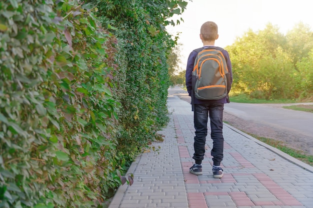 Niño con mochila va a la escuela. vista trasera.