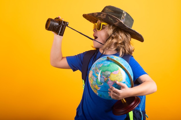 Niño con mochila y explorador de cámara Concepto de exploración y descubrimiento Niño con globo terráqueo Aventura y turismo viajes de ocio Viajes y vacaciones de aventura Niño explorando el mundo