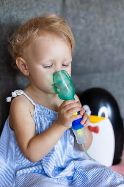 Foto un niño con mocos sostiene una máscara de un nebulizador en sus manos.