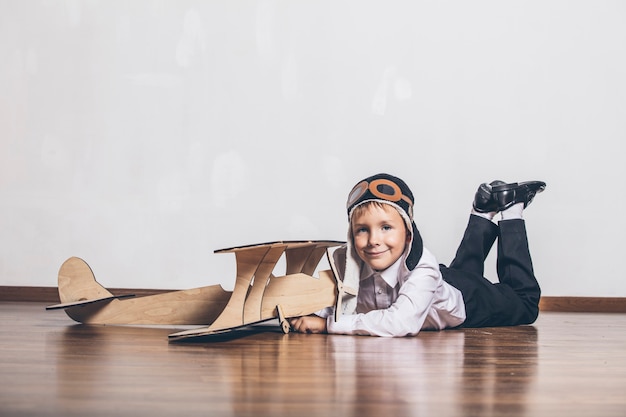 Niño con modelo de avión de madera y gorra con gorra