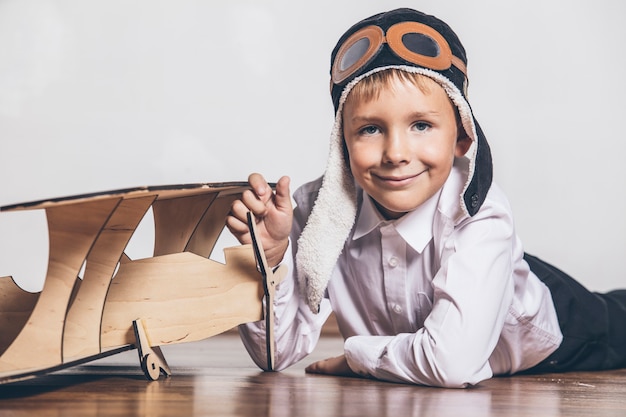 Niño con modelo de avión de madera y gorra con gorra