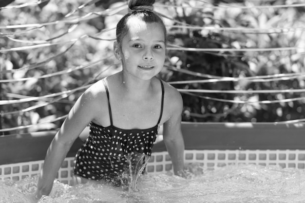 Niño mojado disfruta de un día soleado de verano nadando en la piscina al aire libre