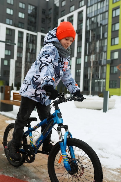 Un niño monta una bicicleta deportiva en la estación fría