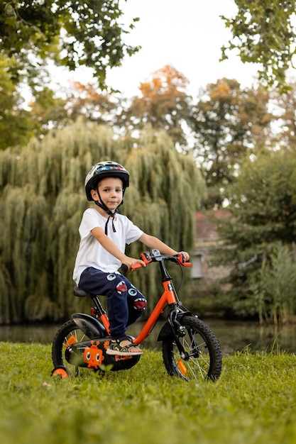 Un niño monta una bicicleta en un parque cerca del lago el día libre del escolar