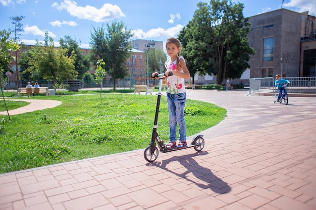 Niño monta un scooter en un parque de verano