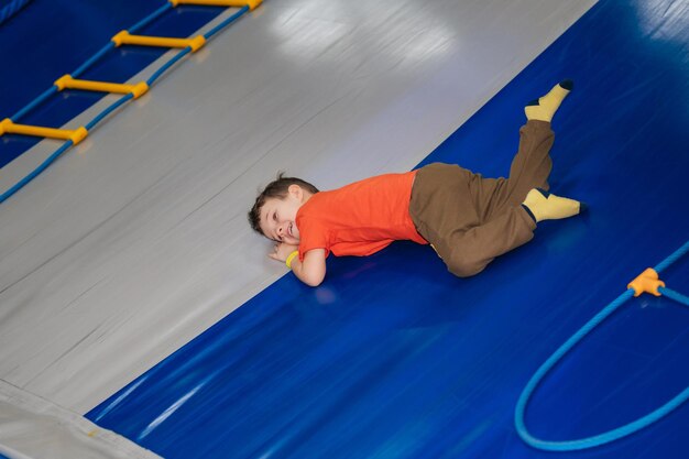 Un niño monta desde un tobogán de gimnasia infantil en un parque infantil en un centro de entretenimiento de juegos Ocio activo Infancia y alegría