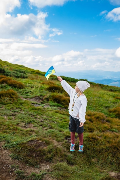 Un niño en una montaña con una bandera ucraniana.