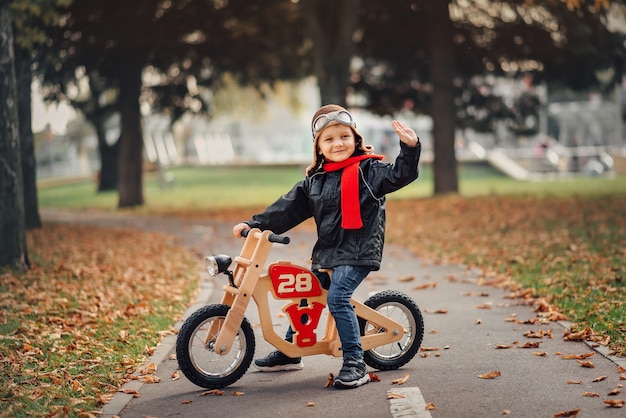 Niño montando una bicicleta de equilibrio en la ciudad en otoño