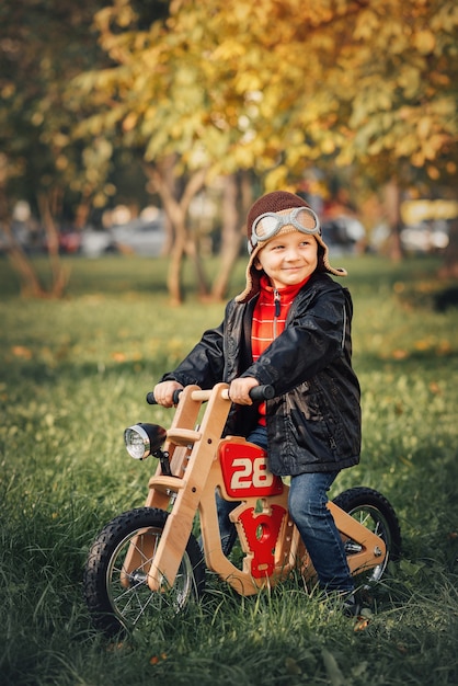 Niño montando una bicicleta de equilibrio en ropa de abrigo en otoño