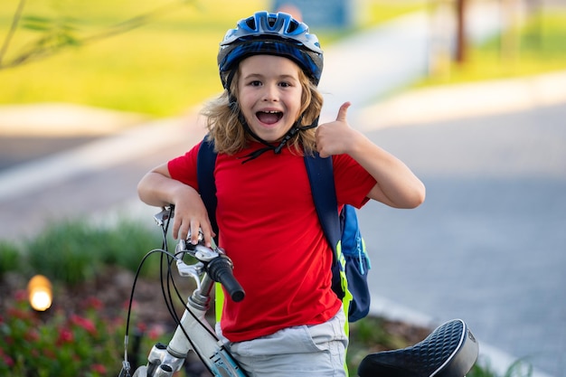 Foto niño montando en bicicleta niño pequeño con casco en bicicleta a lo largo del carril bici feliz lindo niño montando