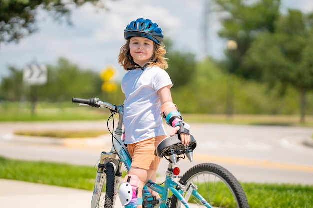Niño montando en bicicleta niño pequeño con casco en bicicleta a lo largo de la ciclovía feliz lindo niño montando