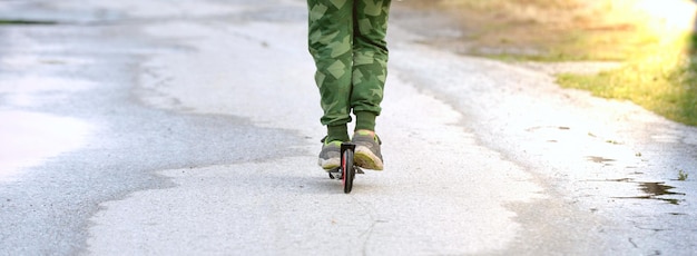 niño montando un scooter en el parkon el camino de la calle