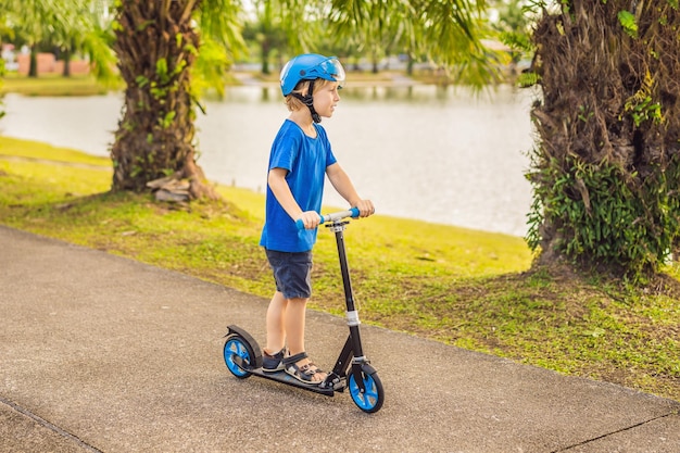 Foto niño montando scooters al aire libre en el verano del parque los niños están felices jugando al aire libre