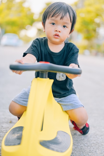 Foto niño montando triciclos. pequeño niño asiático montando tolocar en el patio trasero.