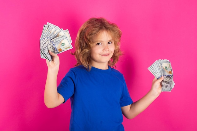 Foto niño con un montón de cientos de dólares aislados en el fondo del estudio concepto de donación y ahorro de caridad y finanzas