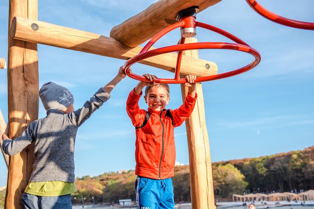 un niño moreno con una sudadera roja cuelga de la barra horizontal, un niño practica deportes