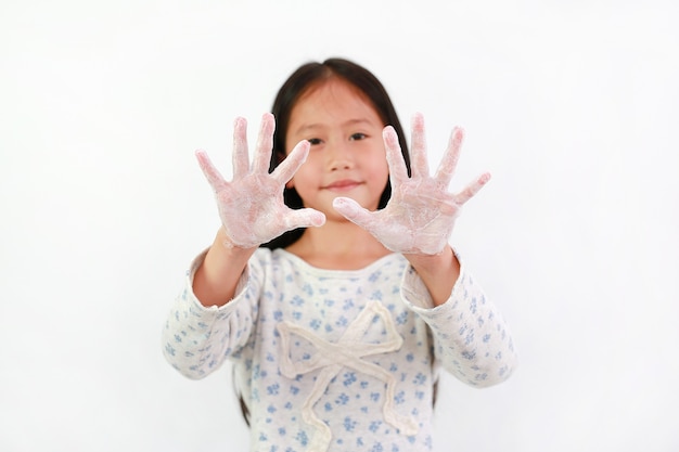 Niño mostrando lavarse las manos con agua y jabón sobre fondo blanco. Concepto de prevención de infecciones de higiene y virus. Centrarse en las manos del niño