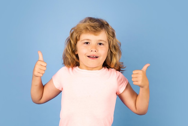 Niño mostrando los pulgares hacia arriba en el estudio de fondo aislado retrato de niño haciendo pulgares arriba signo