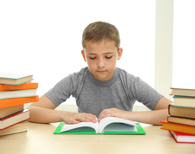 Niño con muchos libros en la escuela.