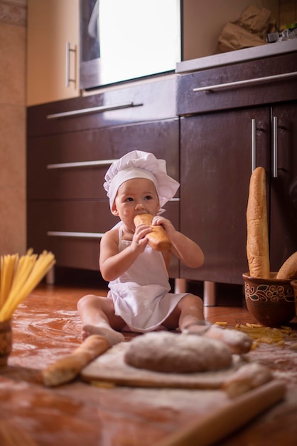 niño muerde un pan disfrazado de cocinero