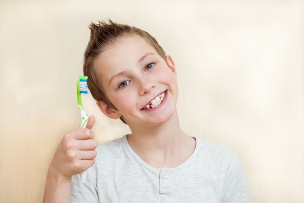 niño muestra sus dientes y cepillo de dientes