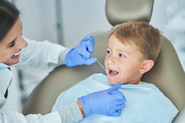 Niño y mujer dentista en la oficina de dentistas