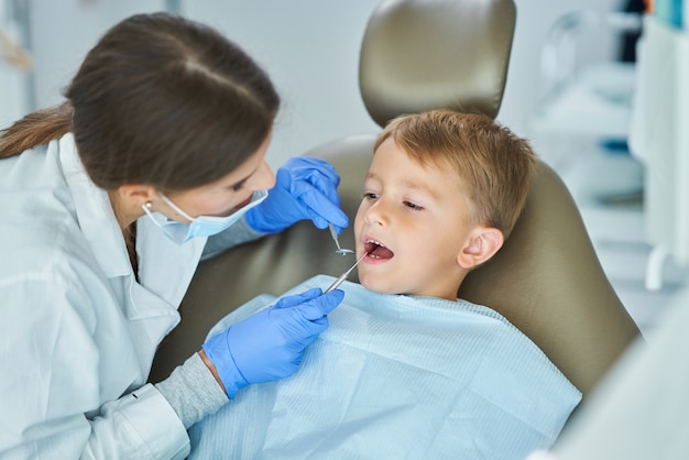 Niño y mujer dentista en la oficina de dentistas