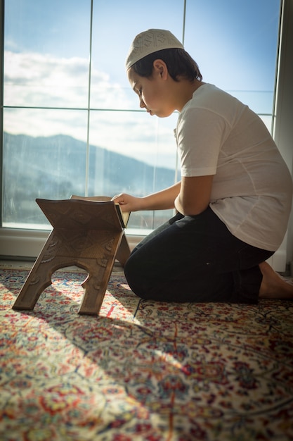 Niño musulmán leyendo el Corán y orando por Dios