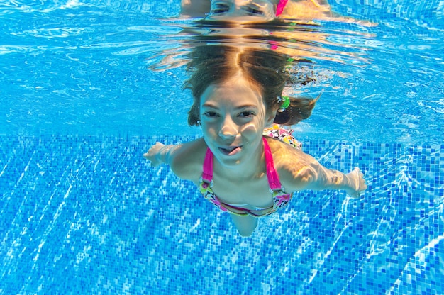 Niño nada en la piscina bajo el agua