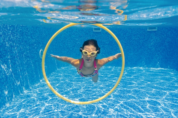 Niño nada en la piscina bajo el agua