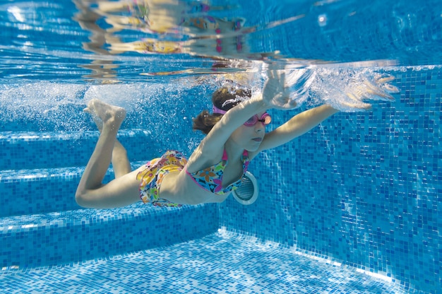 Niño nada en la piscina bajo el agua