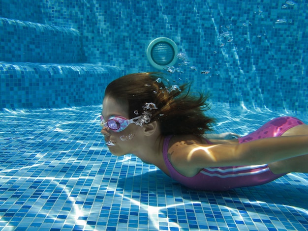 Niño nada en la piscina bajo el agua