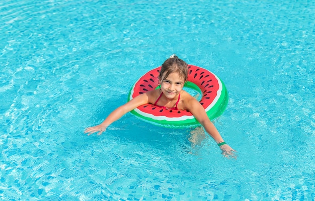 El niño nada en la piscina con un anillo de goma.