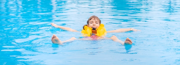 El niño nada en la piscina en verano.