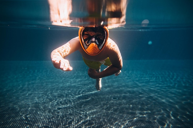 El niño nada y se sumerge en la piscina Enfoque selectivoxA