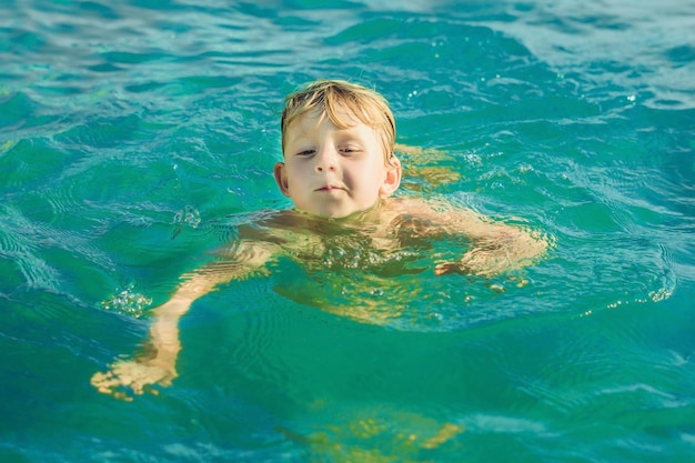 Niño nada en el verano caliente del mar tropical azul