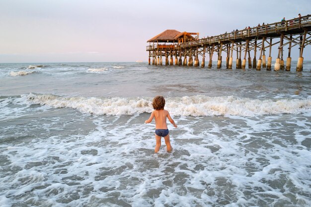 Niño nadando divirtiéndose y saltando en las olas del mar niño divirtiéndose al aire libre