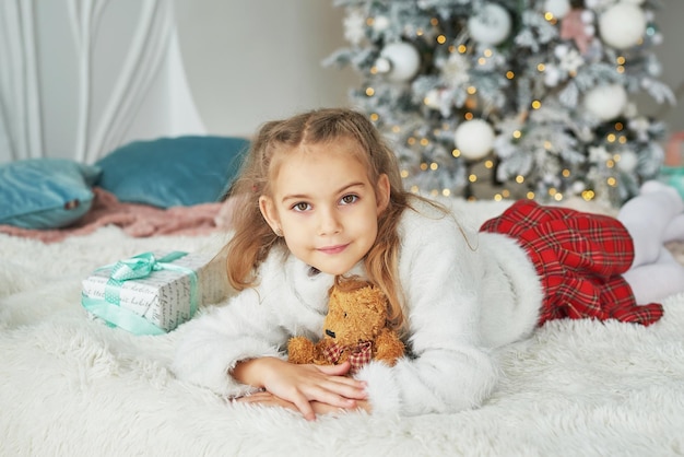 Niño de Navidad en el fondo del árbol de Navidad con osito de peluche de juguete.